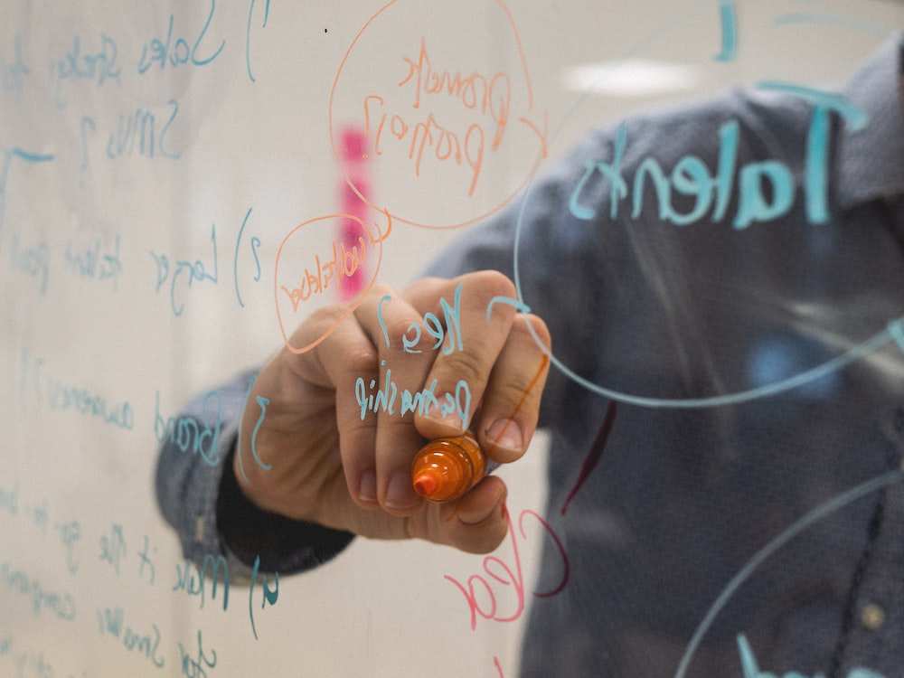 Close-up of a person writing on a clear strategy board, symbolizing planning and innovation in the natural food market.