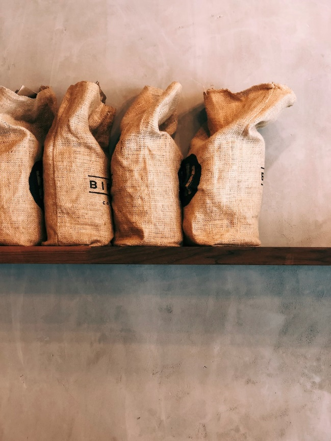 Row of sacks on a wooden shelf, representing sustainable packaging for natural products.