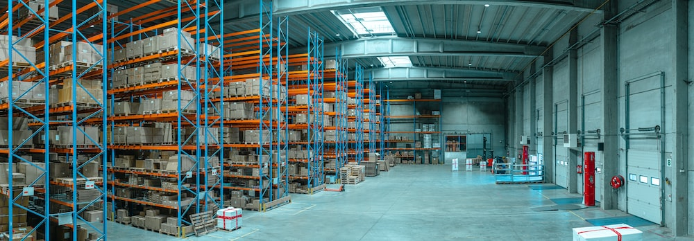 Workers in a warehouse walking along the marked aisles between storage racks.
