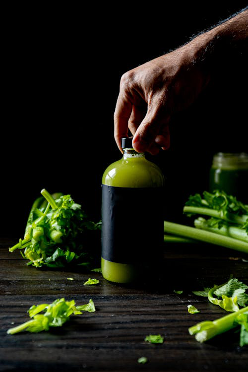 An image of a bottle of natural beverage with fruits and vegetables on a black background  