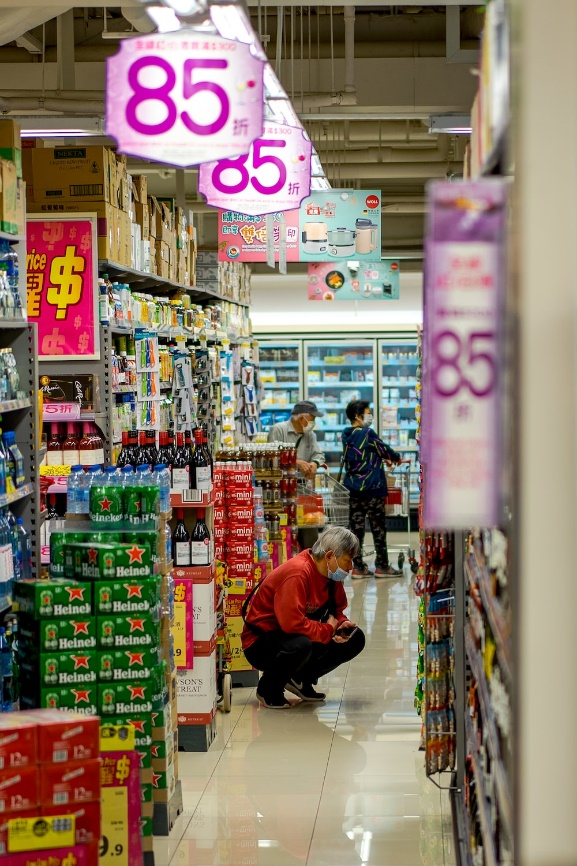 Shopper examining products on a supermarket shelf, representing consumer choices in purchasing.