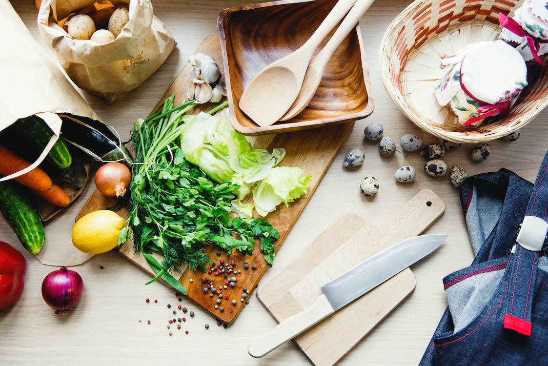 A variety of fresh vegetables and herbs laid out on a kitchen counter.