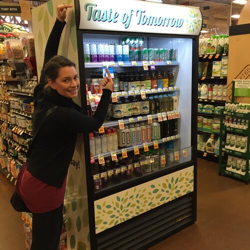 A lady posing with a juice shelf at a supermarket