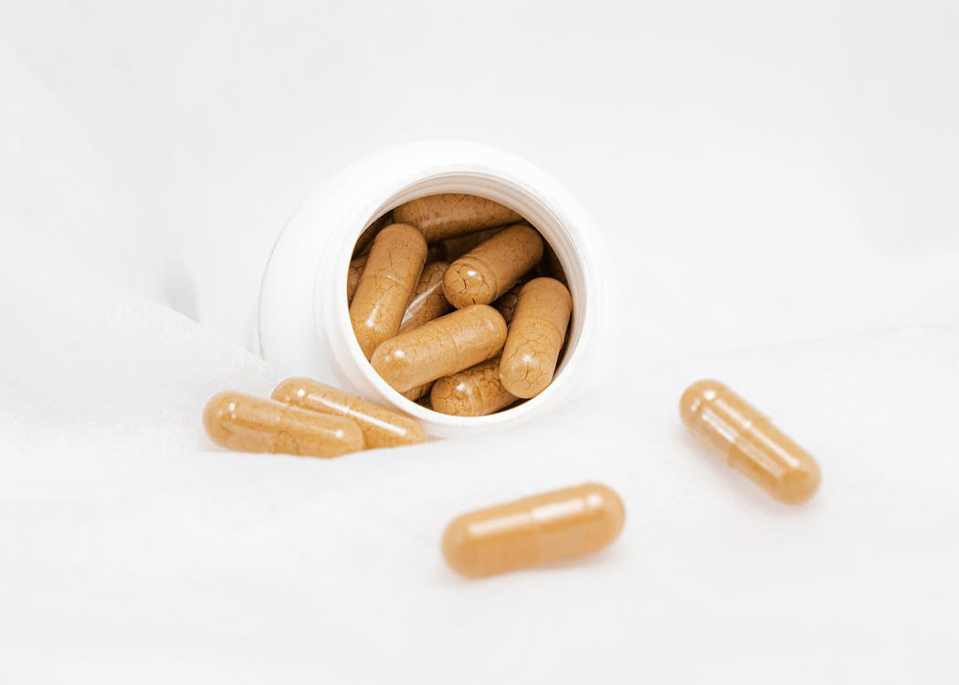 An image showing brown-colored supplements in a white bottle