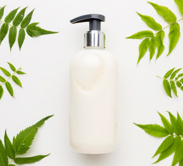 Top view of an organic shampoo surrounded by leaves